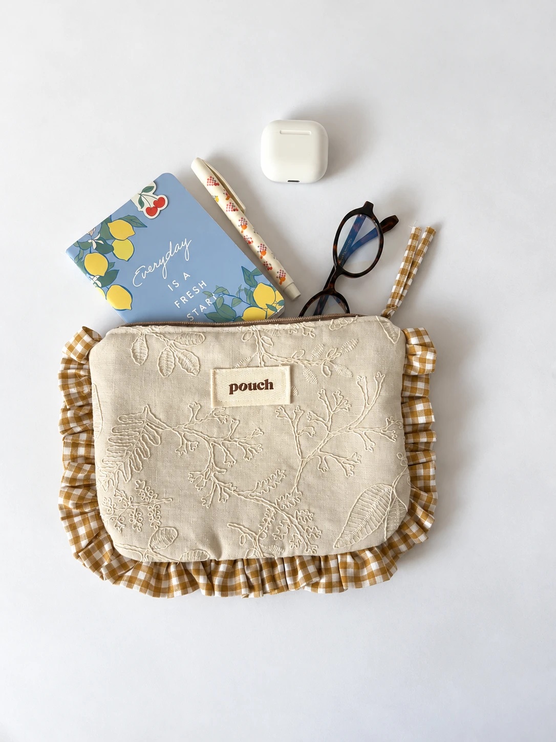 Pouch Magnolia con una libreta, una lapicera, lentes y auriculares